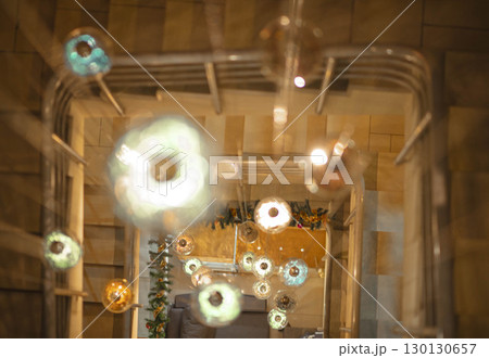 top view of spiral staircase decorated with hanging Christmas lights and holiday garland, soft blur effect with glass orbs in focus, interior design, festive decor, architectural detail top view of spiral staircase decorated with hanging Christmas lights and holiday garland, soft blur effect with glass orbs in focus, interior design, festive decor, architectural detail 130130657