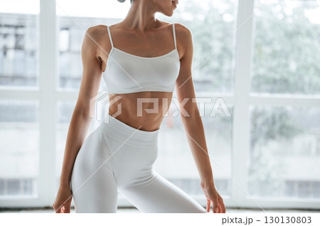 Woman in fitness clothes is standing against window with view Woman in fitness clothes is standing against window with view 130130803