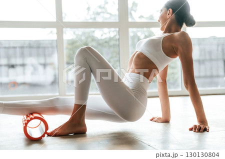 Roller for exercises. Fitness woman is indoors in white clothes 130130804