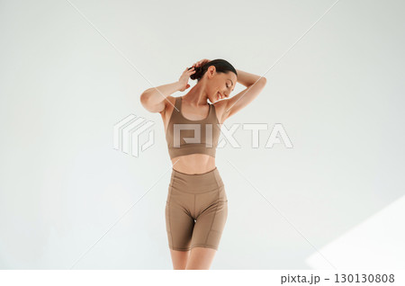 Woman in fitness clothes is standing against white background Woman in fitness clothes is standing against white background 130130808