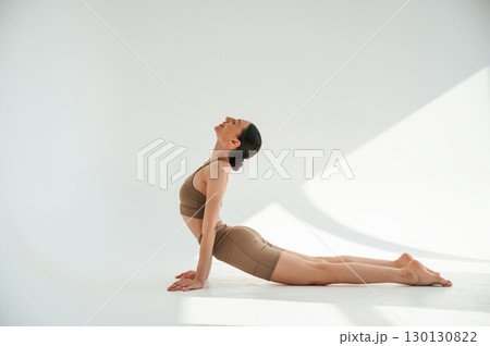 Spine stretching. Young woman is doing fitness yoga indoors against white background 130130822