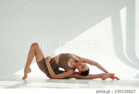 Sporty fitness exercises. Young woman is doing yoga indoors against white background Sporty fitness exercises. Young woman is doing yoga indoors against white background 130130827