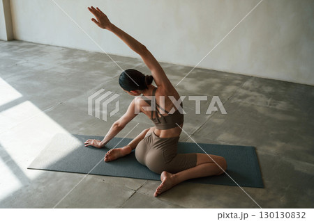 With hands up. Rear view of young woman on yoga mat indoors With hands up. Rear view of young woman on yoga mat indoors 130130832