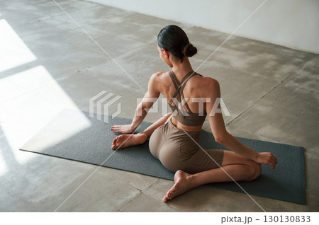 Conception of wellbeing and health care. Rear view of young woman on yoga mat indoors 130130833