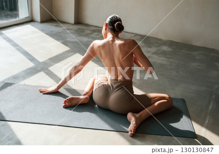 In the sunlight. Back view of sporty woman that is without bra indoors In the sunlight. Back view of sporty woman that is without bra indoors 130130847