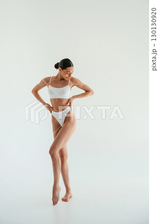 Full height photo. Woman in white underwear with slim body type against white background 130130920