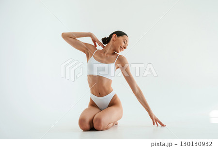 Posing for the camera. Woman in white underwear with slim body type against white background Posing for the camera. Woman in white underwear with slim body type against white background 130130932
