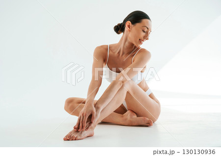 Clean legs after depilation. Woman in white underwear with slim body type against white background 130130936