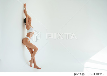 Full height photo. Woman in white underwear with slim body type against white background 130130942