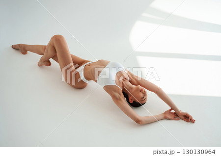 Top view, lying down. Woman in white underwear with slim body type against white background 130130964