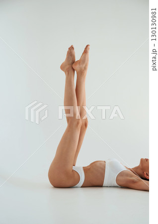 Particle view of legs. Woman in white underwear with slim body type against white background Particle view of legs. Woman in white underwear with slim body type against white background 130130981