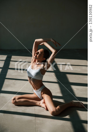 Fitness woman in white clothes is indoors in sunlight Fitness woman in white clothes is indoors in sunlight 130130982