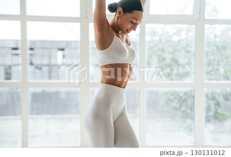 Natural lighting. Woman in fitness clothes is standing against window with view 130131012