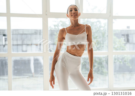 Woman in fitness clothes is standing against window with view 130131016