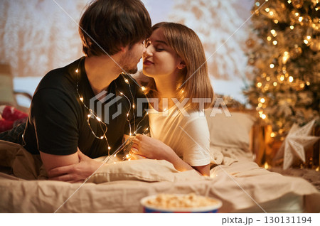 Conception of love. Beautiful young couple indoors, celebrating new year against projector Conception of love. Beautiful young couple indoors, celebrating new year against projector 130131194