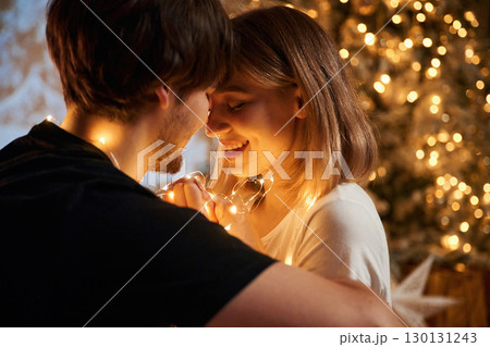 Closeness of the people. Beautiful young couple indoors, celebrating new year against projector Closeness of the people. Beautiful young couple indoors, celebrating new year against projector 130131243