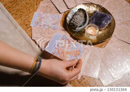 Tarot card reading session with crystals and candles on a wooden table in a cozy room during the evening Tarot card reading session with crystals and candles on a wooden table in a cozy room during the evening 130131369