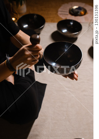 Practitioner uses singing bowls for meditation in a serene studio environment during a mindful evening session 130131396
