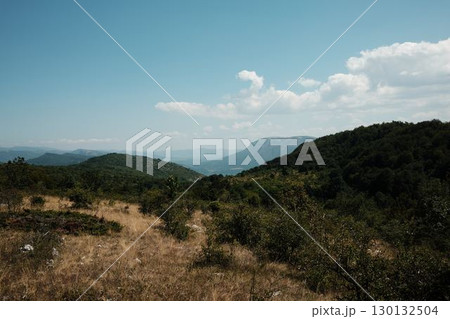 Scenic meadow in Stara Planina, Serbia, with mountains in distance, blue sky and scattered white clouds above Scenic meadow in Stara Planina, Serbia, with mountains in distance, blue sky and scattered white clouds above 130132504