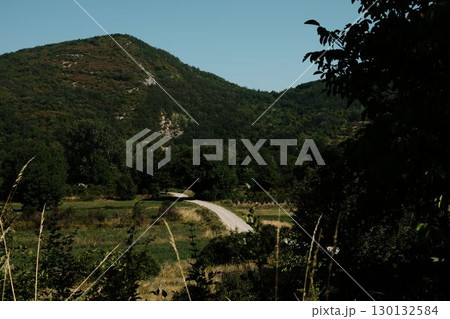 Serene green valley with distant winding road and mountain slopes in Stara Planina, Serbia Serene green valley with distant winding road and mountain slopes in Stara Planina, Serbia 130132584
