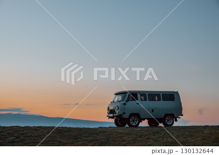 vintage van parked on grassy hill at sunset enjoying serene landscape view. closeup. 130132644