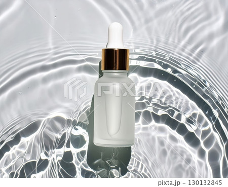 A glass dropper bottle on water surface, top view 130132845