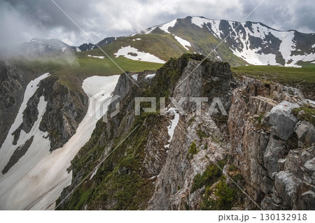 Rocky cliff above a picturesque foggy mountain valley 130132918