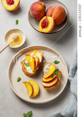 Toasted bruschetta with peach, nectarine, cream cheese or ricotta and honey  on a light background 130133587