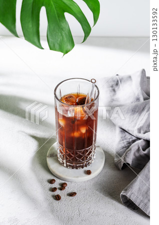 Cold brew coffee tonic in a glass with ice on a light background with coffee beans 130133592