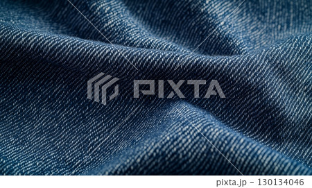 The texture of dark blue denim fabric is prominently displayed, highlighting the woven patterns and natural folds in the material 130134046
