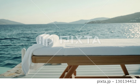 Relaxation awaits on this elegant massage table placed on a sandy beach, overlooking calm waters and distant hills for a perfect escape 130134412