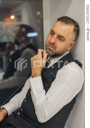 Thoughtful Caucasian man sitting on windowsill in office.  130135002