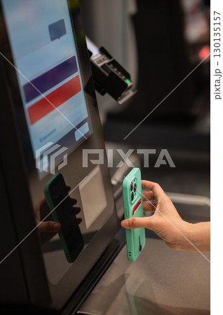 Woman scanning discount on phone at self-checkout. Woman scanning discount on phone at self-checkout. 130135157