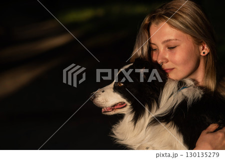 Young Caucasian woman hugging her border collie dog while walking in the park. Young Caucasian woman hugging her border collie dog while walking in the park. 130135279
