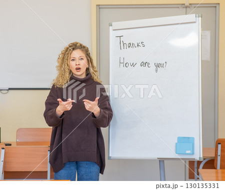Caucasian female teacher communicates in Russian sign language with students.  130135331