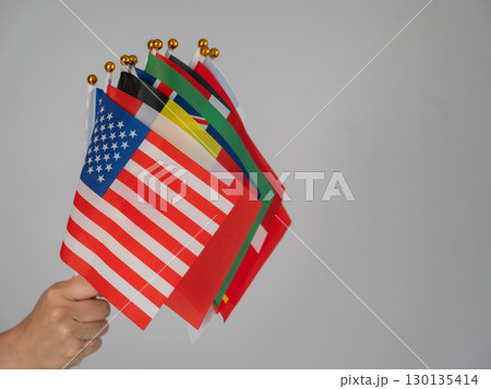 A woman's hand holding a bunch of small flags of different countries. A woman's hand holding a bunch of small flags of different countries. 130135414