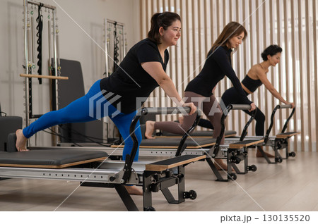 Three Asian women doing Pilates on a reformer.  130135520