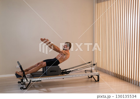 A man doing Pilates on a reformer.  130135534