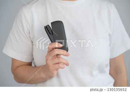 A woman takes a tobacco heating system out of a charger. Electronic cigarette. A woman takes a tobacco heating system out of a charger. Electronic cigarette. 130135652