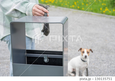 Responsible Dog Owner Disposing of Waste in Park Bin. Responsible Dog Owner Disposing of Waste in Park Bin. 130135751