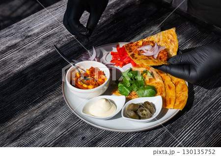 A chef wearing black gloves prepares fajitas. A chef wearing black gloves prepares fajitas. 130135752