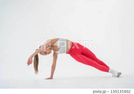 Young woman doing side plank on white background. Young woman doing side plank on white background. 130135802