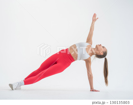 Young woman doing side plank on white background. 130135803