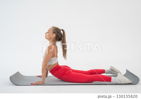 Young woman doing cobra exercises on white background. Young woman doing cobra exercises on white background. 130135820