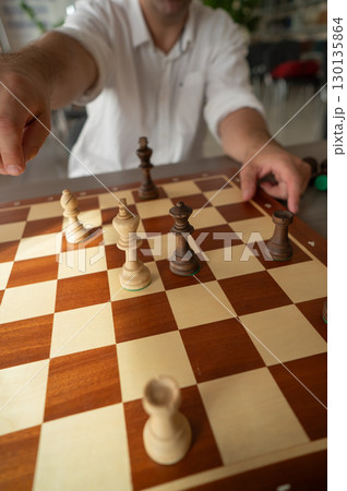 Close up of hands of middle aged caucasian man playing chess.  130135864