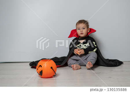 Little Caucasian boy in Dracula costume holding basket for sweets on white background. Trick or treat. Little Caucasian boy in Dracula costume holding basket for sweets on white background. Trick or treat. 130135886