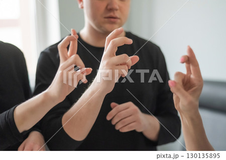 Caucasian woman teaching sign language to man and woman. Caucasian woman teaching sign language to man and woman. 130135895