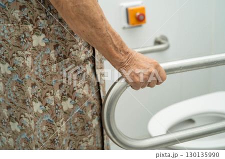 Asian elderly woman patient use toilet support rail in bathroom. 130135990
