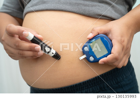 Asian woman injecting herself diabetes injecting insulin in stomach at home. 130135993
