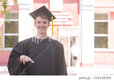 Caucasian young man in graduation gown communicating using sign language. Caucasian young man in graduation gown communicating using sign language. 130136364